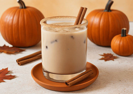 Pumpkin spice white russian cocktail with cinnamon sticks in front of mini pumpkns.